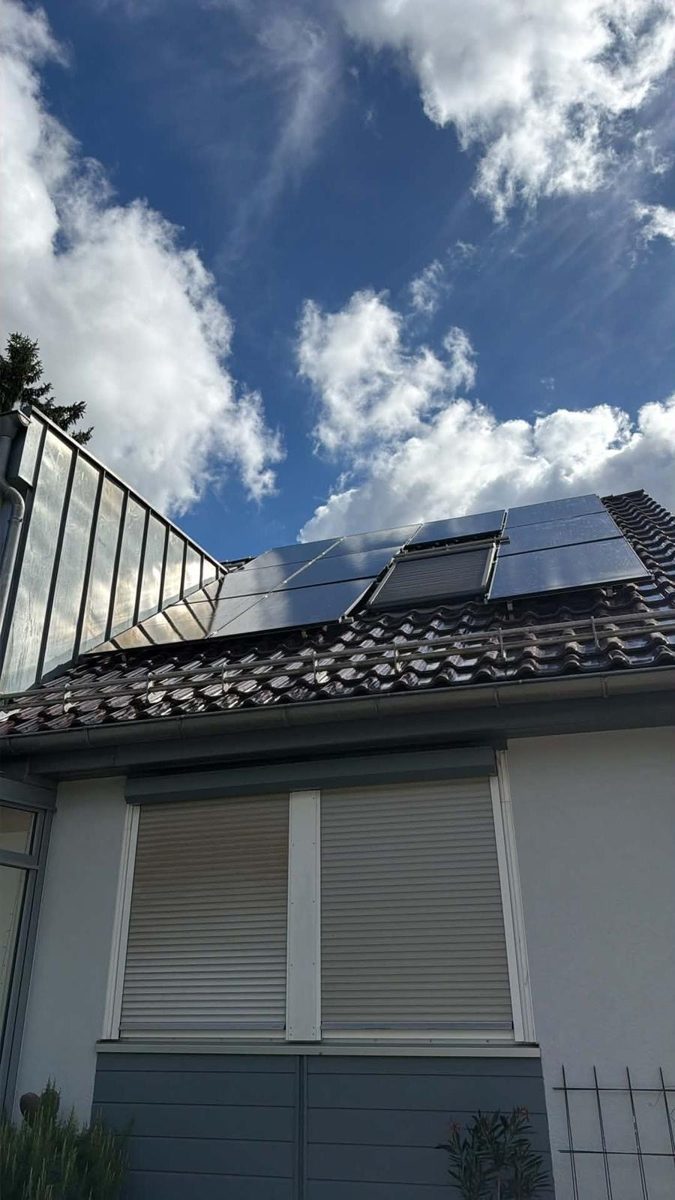 Von Ferdinand Schatz montierte Photovoltaikanlage auf einem Ziegeldach unter blauem Himmel