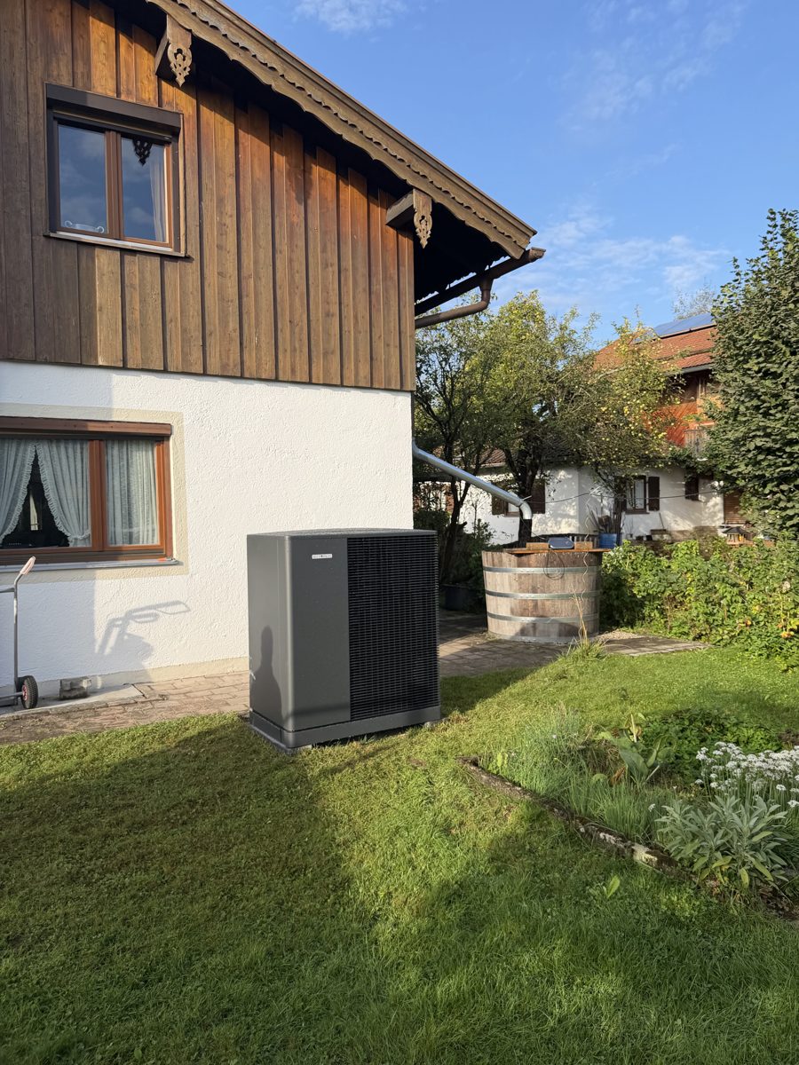 Von Ferdinand Schatz installierte Luft-Wasser-Wärmepumpe vor einem Einfamilienhaus mit Holzfassade